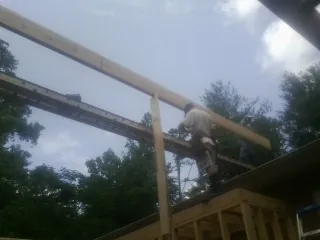 Carpenter setting a ridge beam over a new addition frame — Ice Dam Removal by Roofing Brothers in Reardan
