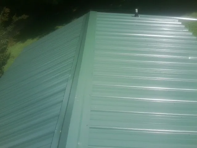 New green metal panels meeting at the ridge of a roof — Flat Roof Repair work by our crew in Reardan