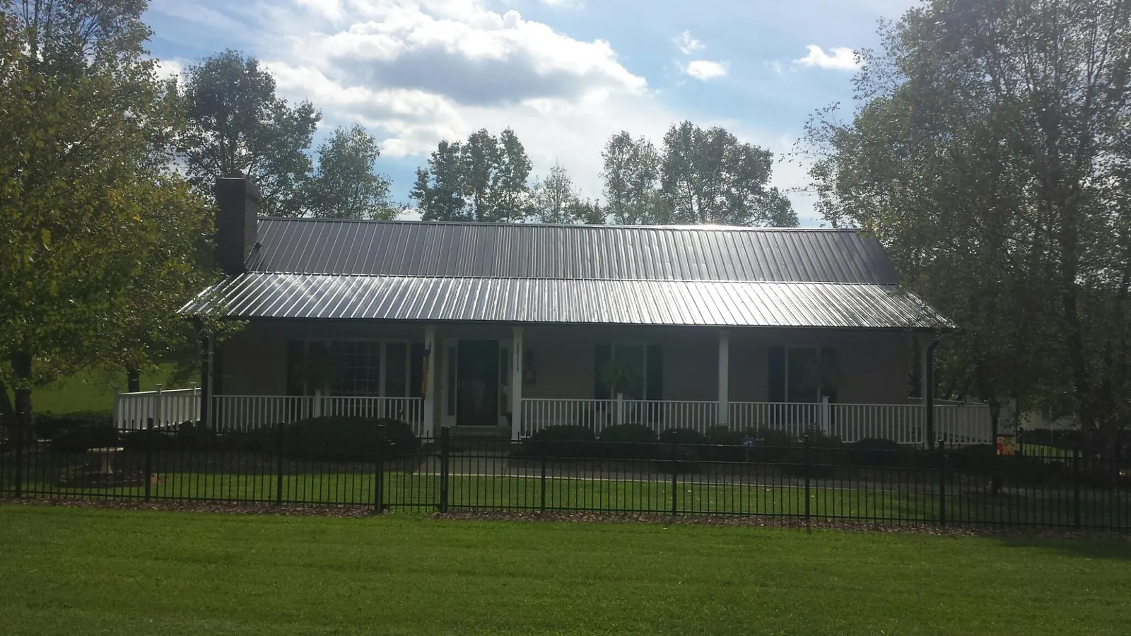 Gray metal roof on a brick ranch with a full width front porch — Gutter Guard Installation work by our crew in Reardan