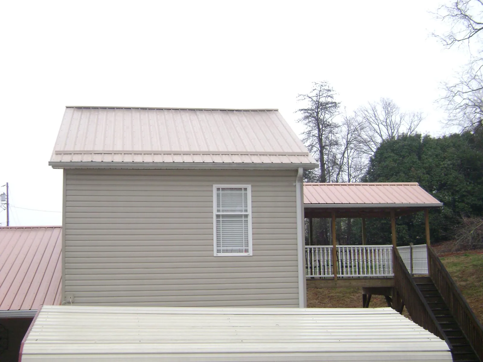 Tan metal roofs on a two story addition and attached porch, from a Roof Replacement job in Reardan