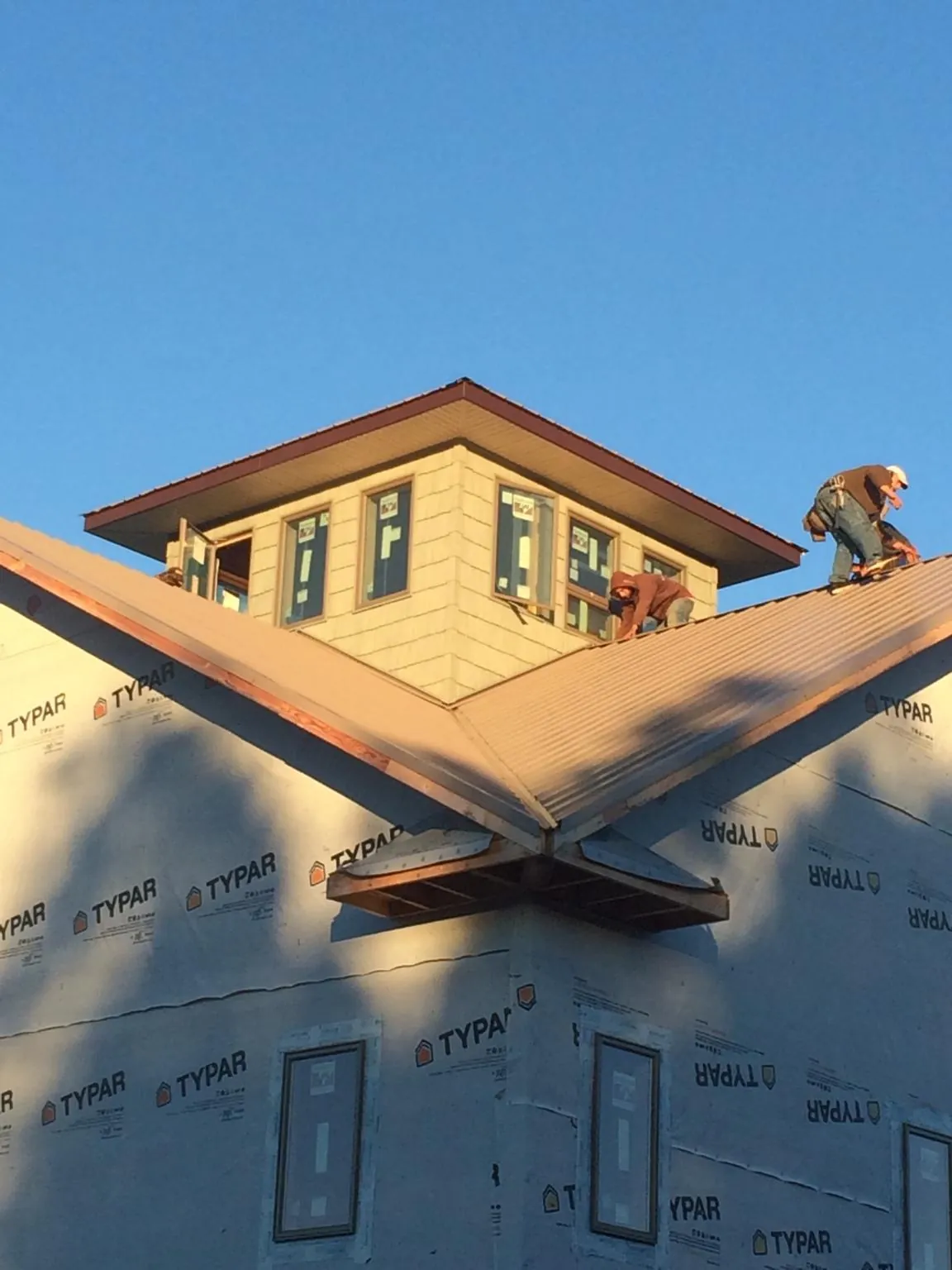 Roofers working around a rooftop cupola on a new metal roof at sunset — Roof Waterproofing in Reardan by Roofing Brothers